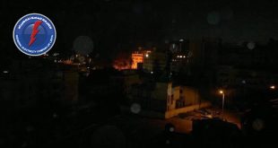 ​صورة ليلية لمنطقة سكنية مظلمة مع شعار الشركة العامة للكهرباء، تعبيرًا عن آلاف بلاغات الأعطال وانقطاع التيار.
