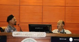 ​صورة فوتوغرافية للفنان والمصمم الليبي محمد علي سيالة أثناء تحدثه في الجلسة الحوارية "الطابع البريدي ذاكرة مرسومة" بمقر المركز الليبي للمحفوظات والدراسات التاريخية.