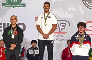 البطل الليبي محمد الساحلي يقف على منصة التتويج المركز الأول متقلدًا الميدالية الذهبية لبطولة العالم للقوة البدنية لوزن 66 كجم ناشئين بجانب الفائزين بالمركزين الثاني والثالث.