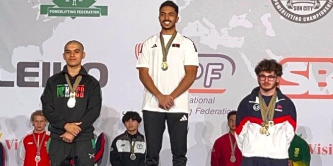 البطل الليبي محمد الساحلي يقف على منصة التتويج المركز الأول متقلدًا الميدالية الذهبية لبطولة العالم للقوة البدنية لوزن 66 كجم ناشئين بجانب الفائزين بالمركزين الثاني والثالث.