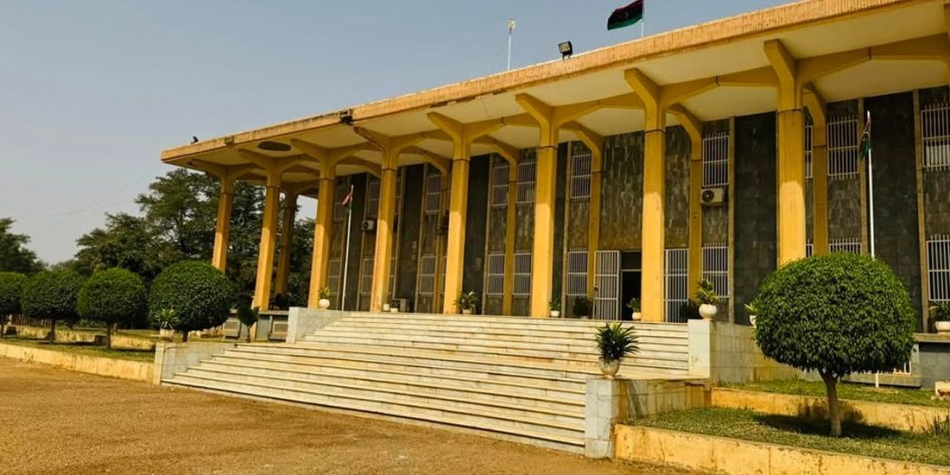 صورة خارجية لمبنى سفارة ليبيا في نيامي مع أعمدة صفراء وعلم ليبيا يرفرف فوقه، تعبيرًا عن خبر تحذير الجالية الليبية من تطورات الأوضاع.