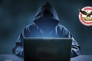 صورة تعبيرية تظهر شخصاً مجهول الهوية يرتدي غطاء رأس (هودي) أسود ويجلس أمام جهاز كمبيوتر محمول (لابتوب