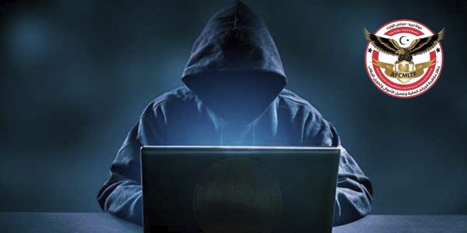 صورة تعبيرية تظهر شخصاً مجهول الهوية يرتدي غطاء رأس (هودي) أسود ويجلس أمام جهاز كمبيوتر محمول (لابتوب