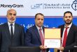 المدير العام المكلف لمصرف الجمهورية ومسؤولون آخرون يقفون جنبًا إلى جنب أثناء توقيع أو التقاط صورة تذكارية مع وثيقة اتفاقية الشراكة مع موني غرام أمام خلفية تحمل شعاري مصرف الجمهورية وMoneyGram.