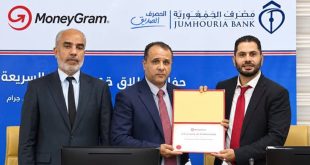 المدير العام المكلف لمصرف الجمهورية ومسؤولون آخرون يقفون جنبًا إلى جنب أثناء توقيع أو التقاط صورة تذكارية مع وثيقة اتفاقية الشراكة مع موني غرام أمام خلفية تحمل شعاري مصرف الجمهورية وMoneyGram.