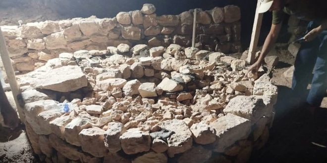 عامل أو مختص بالترميم أثناء العمل على إعادة بناء وتجهيز الحواف والحجارة الدائرية لخزان مياه جوفي قديم مبني من الأحجار التاريخية في مسجد أثري.