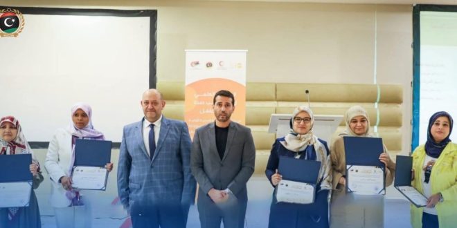 مجموعة من الكوادر الطبية والمسؤولين بوزارة الصحة يتوسطون المنصة حاملين شهادات تقدير خلال احتفالية إطلاق كتيب صحة الأم والطفل.