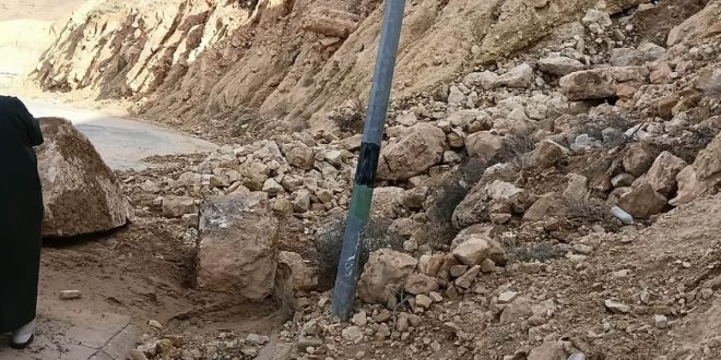 صخور وأتربة ممتدة من منحدر جبلي تغلق طريقًا زفتيًا مع وجود عمود إنارة وسقوط أحجار ضخمة