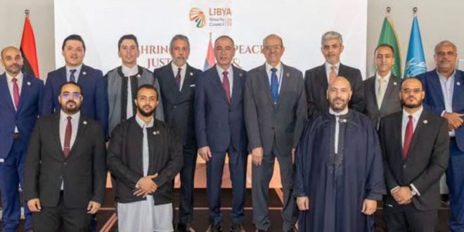 صورة جماعية للمكلف بتسيير ديوان وزارة الخارجية الليبية الطاهر الباعور وأعضاء الوفد الليبي والدبلوماسيين المشاركين في حفل تدشين حملة ترشح ليبيا لمجلس الأمن خلف خلفية تحمل شعار الحملة