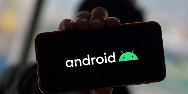 يد تحمل هاتفاً ذكياً يعرض على شاشته باللون الأسود كلمة "android" باللون الأبيض بجانب شعار أندرويد الأخضر الشهير