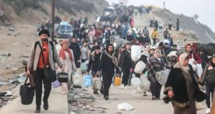 حشداً كبيراً من الفلسطينيين يسيرون على طريق مدمر في قطاع غزة، ويحملون ممتلكاتهم الشخصية، في مشهد يعكس النزوح القسري
