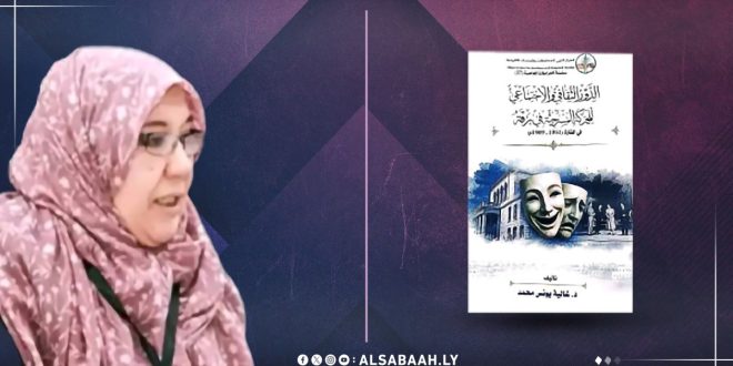 صورة لحدث ثقافي لمنصة الصباح الإخبارية تُظهر الكاتبة غالية الذرعاني وهي تتحدث بجانب غلاف كتابها الذي يحمل عنوان "الدور الثقافي والاجتماعي للحركة المسرحية في برقة". النص البديل يصف الكاتبة المحجبة وهي تشرح كتابها المصور بأقنعة مسرحية وواجهة مسرح