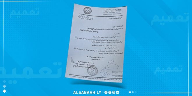 ​صورة لوثيقة رسمية تتضمن تعميمًا صادراً عن ديوان مجلس الوزراء بحكومة الوحدة الوطنية، معروضة على خلفية زرقاء تصميمية تحمل تكرار كلمة "تعميم" وشعار موقع منصة الصباح (ALSABAAH.LY). ينص التعميم المودع والموقع رسمياً على حظر التعامل مع هيئة اعتماد المؤسسات الصحية وجهاز الأمن القومي إلا بعد موافقة رئيس الوزراء.