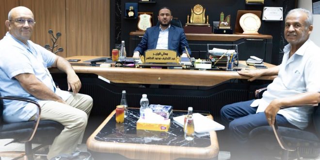وزير الزراعة عبد اللطيف الطاهر يجلس خلف مكتبه وبجانبه الخبير الأمريكي أحمد الطاهر رحومة ومسؤول آخر في اجتماع لمناقشة تداول المبيدات.