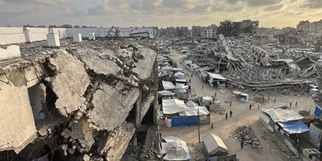 لقطة جوية لدمار واسع وركام مبانٍ سكنية مهدومة في قطاع غزة تتوسطها خيام النازحين وطريق ترابي وسط المباني المتضررة.