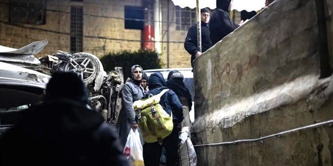 عائلات فلسطينية تغادر منازلها ليلاً سيراً على الأقدام حاملة أمتعتها في مدينة الخليل.