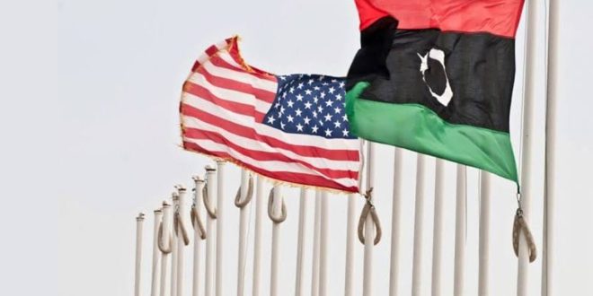 العلم الليبي والعلم الأمريكي يرفرفان جنباً إلى جنب على ساريتين في الهواء الطلق