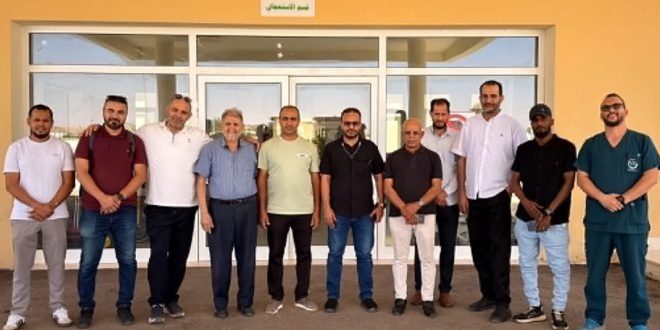 صورة جماعية لطاقم طبي وفني متخصص أمام مدخل مركز "صالح بنخيلة" الطبي بمدينة الكفرة.