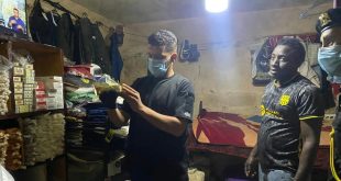 عنصر من دوريات الحرس البلدي يفحص أكياس ومواد في موقع مخالف بحضور أحد العمال المخالفين ورجل أمن
