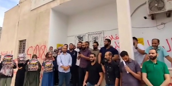 صورة لمجموعة من الأطباء والطبيبات خلال وقفة احتجاجية أمام مقر النقابة العامة للأطباء في منطقة بن عاشور بطرابلس وهم يرفعون اللافتات.