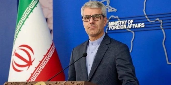 صورة رسمية للمتحدث باسم وزارة الخارجية الإيرانية إسماعيل بقائي أثناء وقوفه أمام المنصة والعلم الإيراني