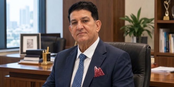 ​صورة للدكتور محمد شرف الدين الفيتوري، أستاذ الإعلام، في مكتبه، يرتدي بدلة زرقاء وربطة عنق، وذلك في سياق خبر عودته لمنزله بعد أسبوع من الغياب