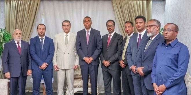 صورة فوتوغرافية لرئيس الوزراء الصومالي حمزة عبدي بري ووفد وزارة الصناعة والمعادن الليبي يظهرون وقوفاً أثناء اجتماعهم في مقديشو لبحث الشراكة الاقتصادية.