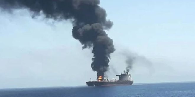 ​صورة لقاطرة بحرية تشتعل فيها النيران قبالة سواحل دولة الإمارات العربية المتحدة. يظهر عمود كثيف من الدخان الأسود يتصاعد من القاطرة المنكوبة، مما يشير إلى وقوع هجوم أو حادث على متنها.