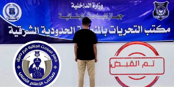 ​صورة توثيقية لمشتبه به يقف بظهره أمام لوحة رسمية لجهاز المباحث الجنائية (مكتب التحريات بالمنطقة الحدودية الشرقية طبرق)، مرفقة بختم "تم القبض" وشعار الجهات الأمنية.