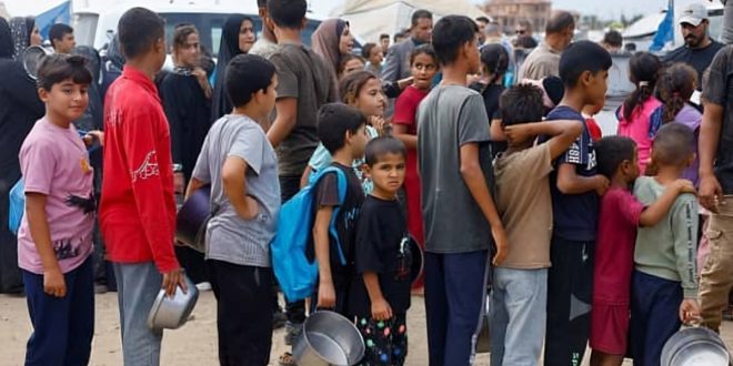 ​صورة تُظهر عشرات الأشخاص، غالبيتهم من الأطفال، يصطفون في طابور طويل للحصول على مساعدات غذائية من برنامج الأغذية العالمي في قطاع غزة.