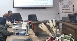 صورة لاجتماع وورشة عمل تربوية تجلس فيها مجموعة من المشاركين حول طاولة اجتماعات خشبية يعلوها العلم الليبي وشعار المصلحة، وتظهر في الخلفية شاشة عرض إلكترونية تعرض شريحة بعنوان "أولاً: الواقع الحالي لنظام الامتحانات والأسئلة"، وبجانبها لافتة تعريفية تابعة لوزارة التربية والتعليم بمصلحة التفتيش والتوجيه التربوي.