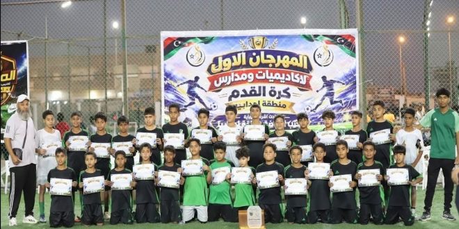 صورة جماعية للاعبي أكاديميات كرة القدم الناشئين في إجدابيا وهم يحملون شهادات التقدير بحضور مشرفيهم أمام لافتة المهرجان الأول.